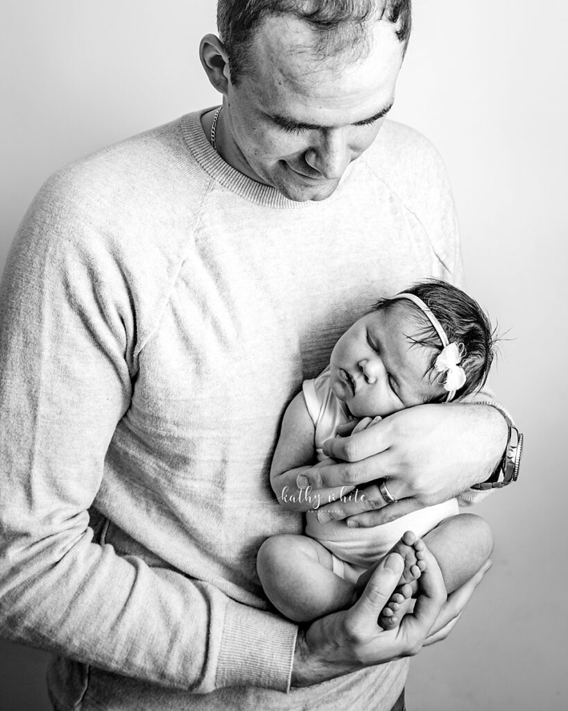 New dad holding sleeping baby girl in his arms.

