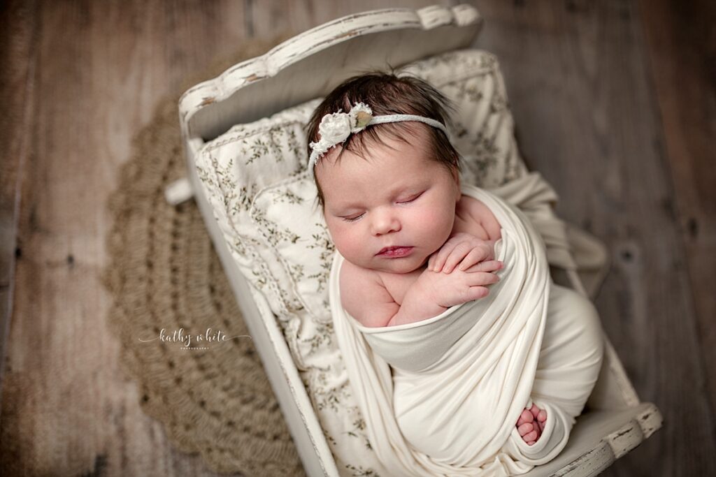 Newborn girl sleeping in crib in Kathy White Photography's studio.