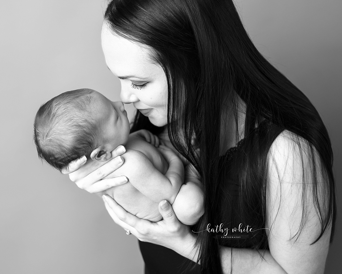 Black and white image of postpardum mom holding sleeping baby close