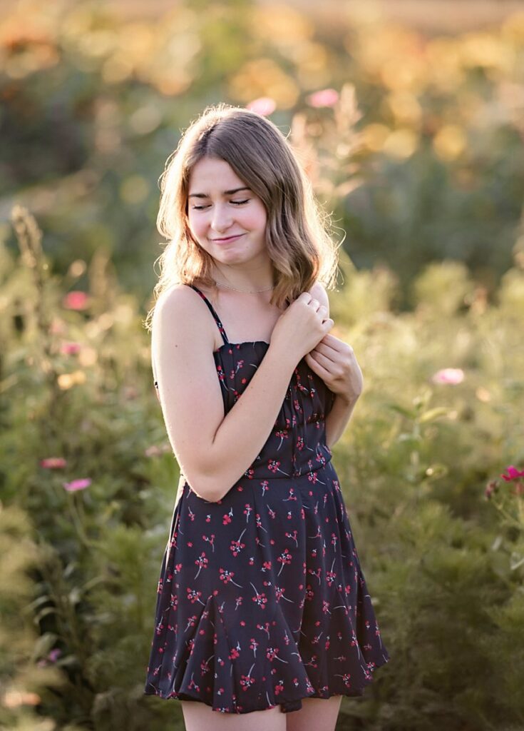 Shy teenaged girl smiling down at the ground in a beautiful garden in Middletown, Maryland.