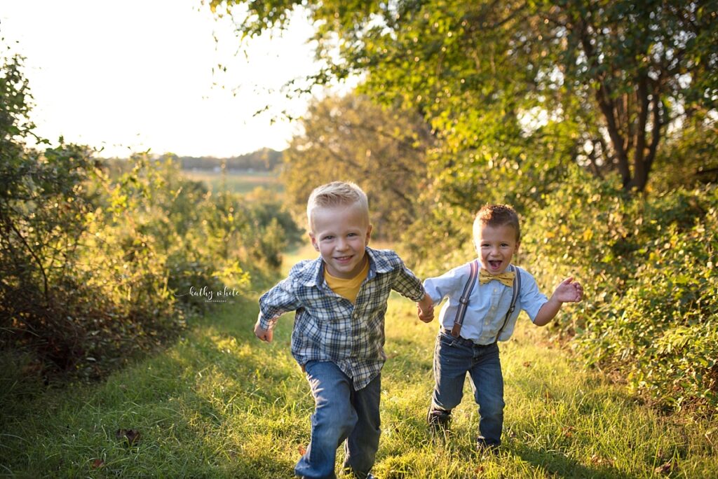 Smiling children running toward the photographer during a photo shoot in a wooded area in Maryland.