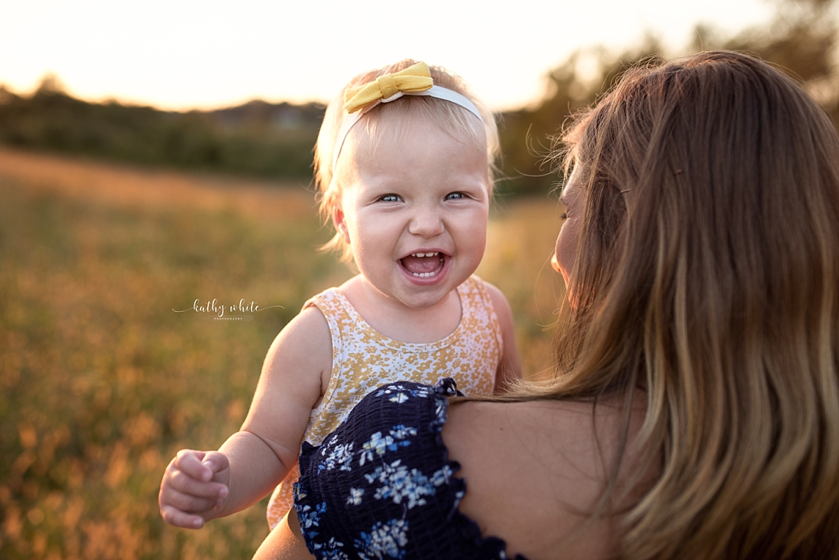 Laughing baby girl being held by her mother during a photo shoot.