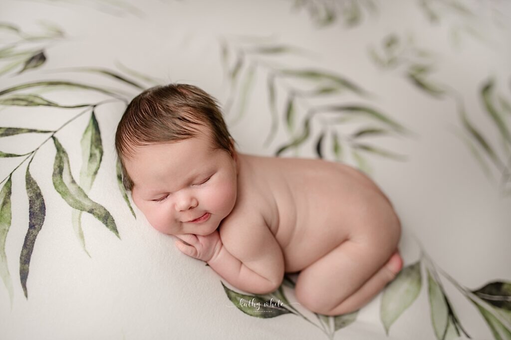 Smiling baby who recently went through childbirth, posed on a blanket and is sleeping.