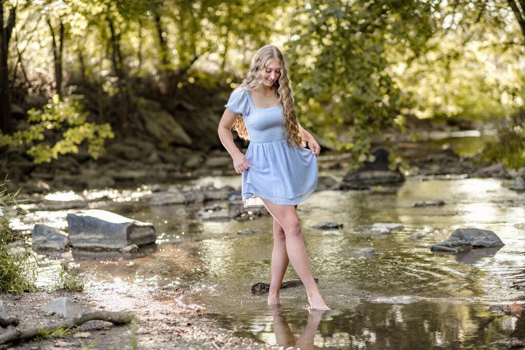 Smiling high school senior wading in a creek in Frederick, Maryland.
